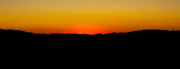 Horizon line on hilly terrain after sunset. Evening sky in the last rays. Abstract night horizon line background. No sun, only light. - 写真・画像