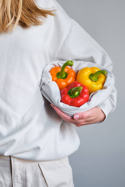 The girl holds colored bell pepper in her hands. Ripe fresh big sweet pepper. Healthy food, organic vegetables. Natural vitamins, raw ingredient for eating. Handpicked bio capsicum - 写真・画像