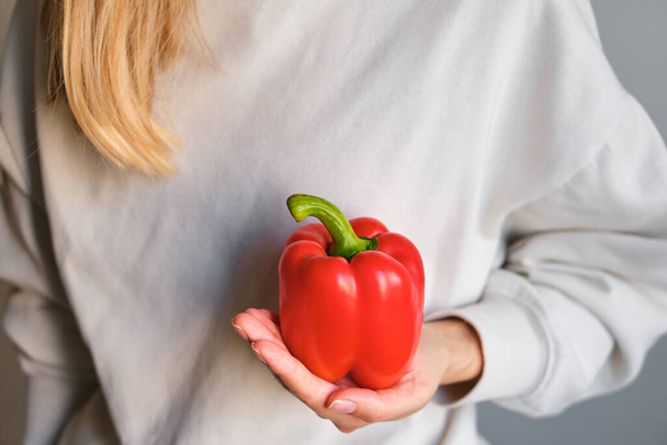 The girl holds colored bell pepper in her hands. Ripe fresh big sweet pepper. Healthy food, organic vegetables. Natural vitamins, raw ingredient for eating. Handpicked bio capsicum - Photo, Image
