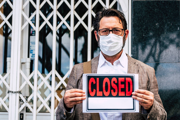 Adult professional businessman with closed sign outside his store for coronavirus economy crisis emergency for lockdown at home  - Фото, изображение