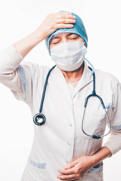 Senior nurse is having a bad headache and holds hand on forehead - isolated on white - Φωτογραφία, εικόνα