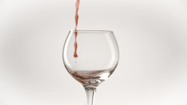 - Şarap. Beyaz zemin üzerine şarap kadehi dökülen kırmızı şarap. Gül şarabı bardağa döküldü. Yakın çekim. Yavaş çekim - Video, Çekim