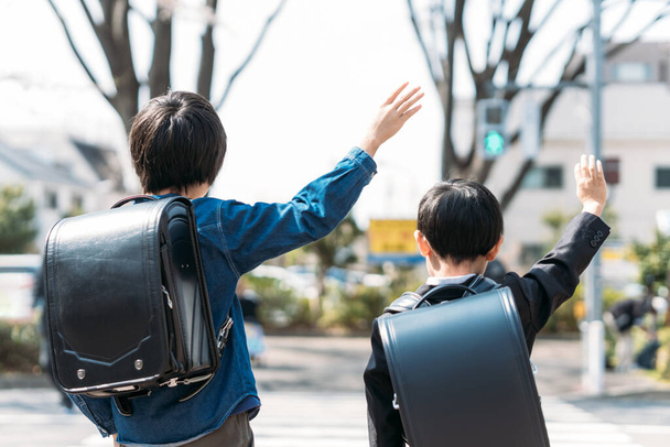 Японські старшокласники і першокласники піднімають руки на перехресті - Фото, зображення