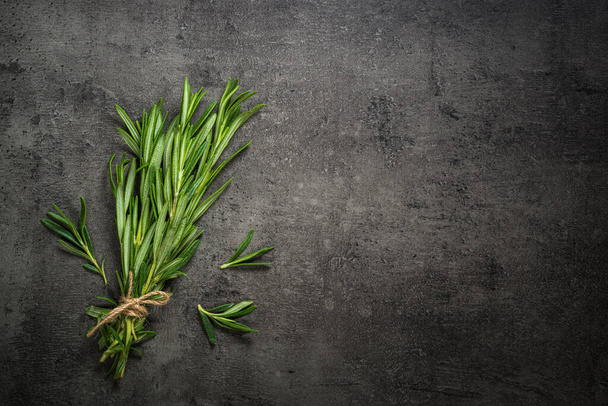 Rosemary sprig on a black kitchen table. - Фото, изображение