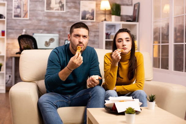 junges Paar isst gebratenes Huhn vor dem Fernseher - Foto, Bild