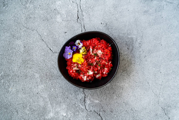 Beetroot Risotto with Edible Flowers and Parmesan Cheese made with Organic Beet in Black Ceramic Bowl. Healthy Organic Food. - 写真・画像