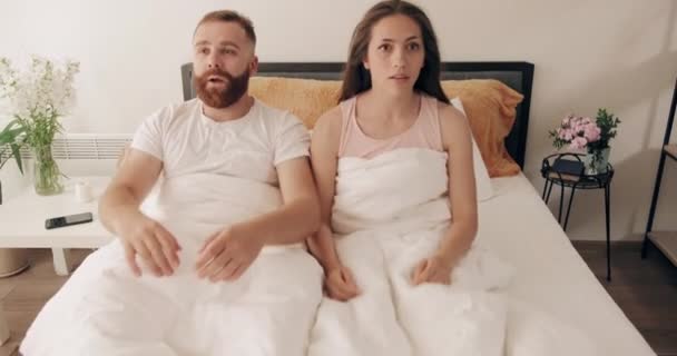 Portrait of young couple understanding that they overslept and panicking. Funny man and woman waking up and started screaming and holding their head on bed.Concept of lifestyle. - Záběry, video