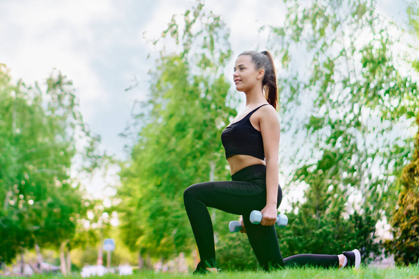 Girl Exercising with Dumbbells Standing on grass in park - Photo, Image