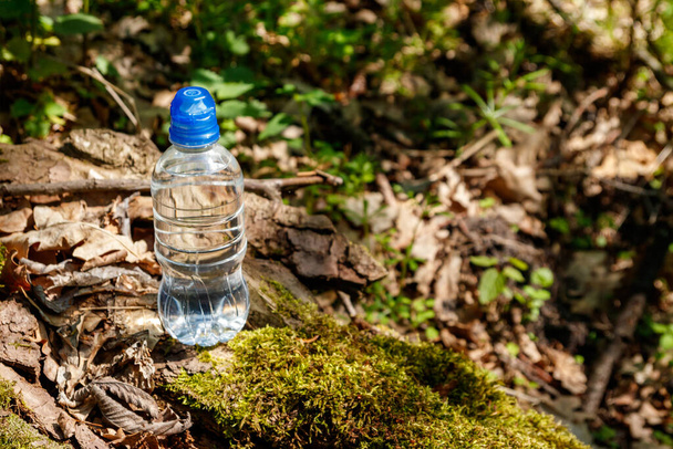 Plastikowa butelka ze słodką wodą pitną na zielonym tle lasu - Zdjęcie, obraz