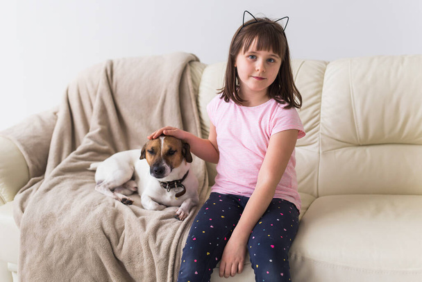Child girl with cute dog jack russell terrier on the couch. Pets , children and home concept. - Φωτογραφία, εικόνα
