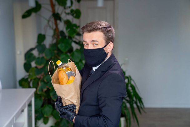 Businessman in black mask holding package of food - 写真・画像