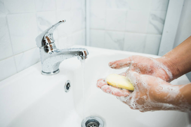 石鹸で手を洗う男性の手を閉じます.コロナウイルス予防のために. - 写真・画像
