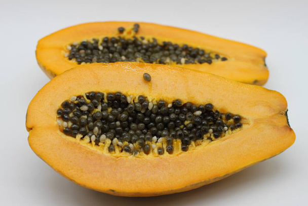 papaya gesneden in de helft geïsoleerd op witte achtergrond - Foto, afbeelding