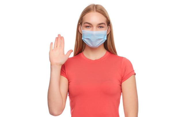 Hastalıktan korunmak için maske takan ve Corona virüsünü durdurmak için el hareketi yapan bir kız. Coronavirus konsepti. - Fotoğraf, Görsel