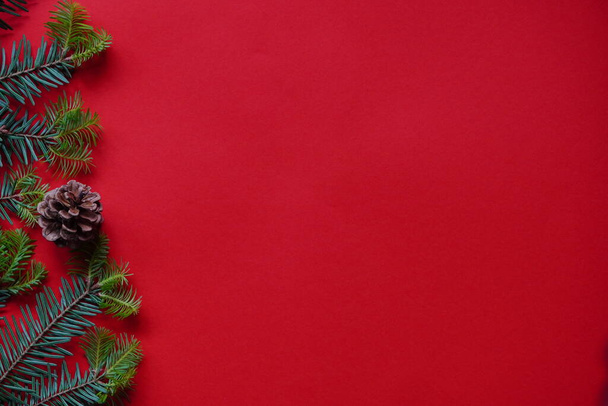 Kerst decoraties lay-out of plat met sparren takken en kegels op rode achtergrond.Eco natuurlijke frame. winter, nieuwjaar Vakantie concept als top view, copyspace.greeting kaart template, banner mockup - Foto, afbeelding