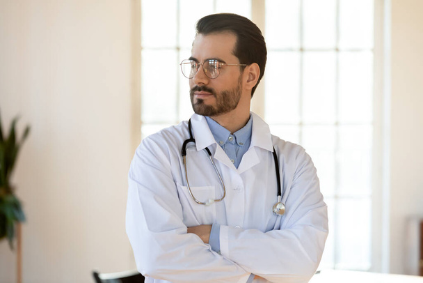Umsichtiger männlicher Arzt blickt in die Ferne oder visualisiert - Foto, Bild