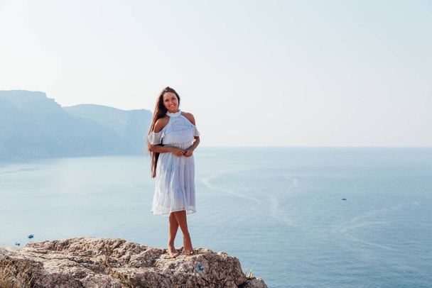 kaunis ruskettunut nainen sininen mekko päälle kalliolla meren rannalla
 - Valokuva, kuva