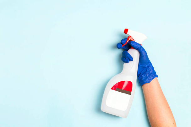 Hand in rubber glove holds a bottle with antiseptic spray on a blue background. Disinfectant concept. Coronavirus precaution. - Photo, image