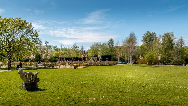 Randers, Danimarka - 09 Maj 2020: The Doctor Park in Randers. İnsanlar doğada oturup kahve içiyorlar. Parkta piknik. Orman arka planda. Çocuklar oyun bahçesinde oynuyor, yeşil renkler ve mavi gökyüzü. - Fotoğraf, Görsel