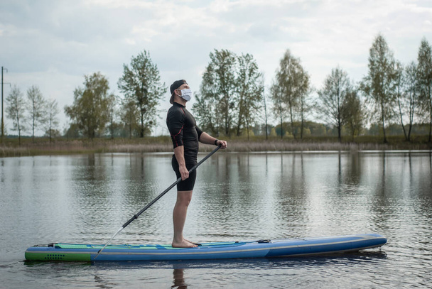 спортсмен в медичній масці веслування весла, стоячи на дошці, профілактика ковадла
, - Фото, зображення