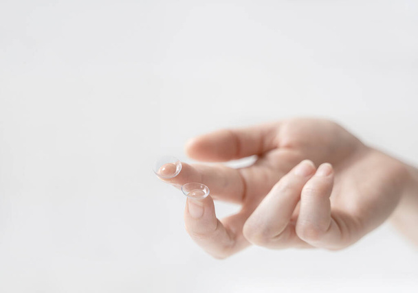 a pair of contact lenses on the index finger of the hand. Using contact lenses to correct vision. - 写真・画像