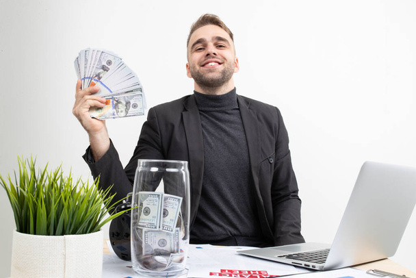 A guy with business clothes shows the earnings while sitting at the workplace - Valokuva, kuva
