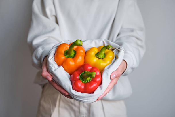The girl holds colored bell pepper in her hands. Ripe fresh big sweet pepper. Healthy food, organic vegetables. Natural vitamins, raw ingredient for eating. Handpicked bio capsicum - Foto, immagini