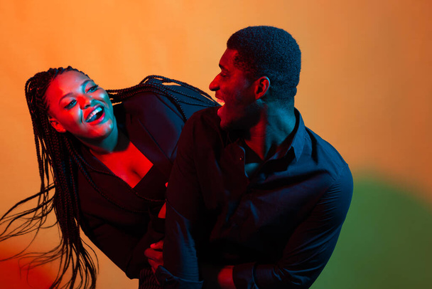 Retrato de neón oscuro de un joven afroamericano hombre y mujer. Luz roja y azul
. - Foto, imagen