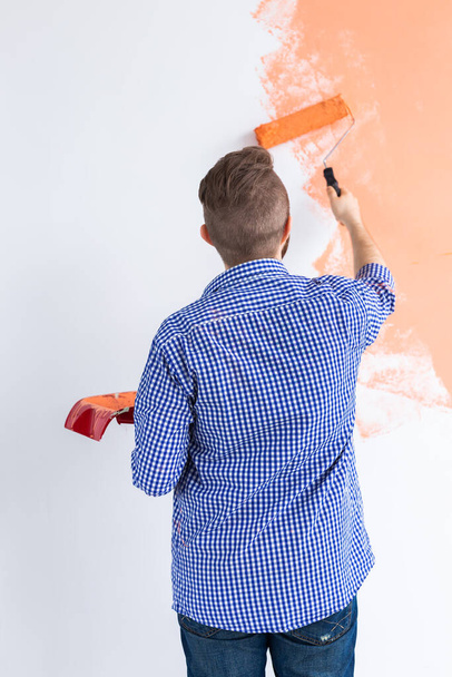 Hombre pintando las paredes de un nuevo hogar. Concepto de renovación, reparación y redecoración. Vista trasera
. - Foto, imagen