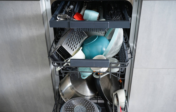 Otwarta zmywarka z czystymi naczyniami w kuchni domowej, widok z przodu. - Zdjęcie, obraz