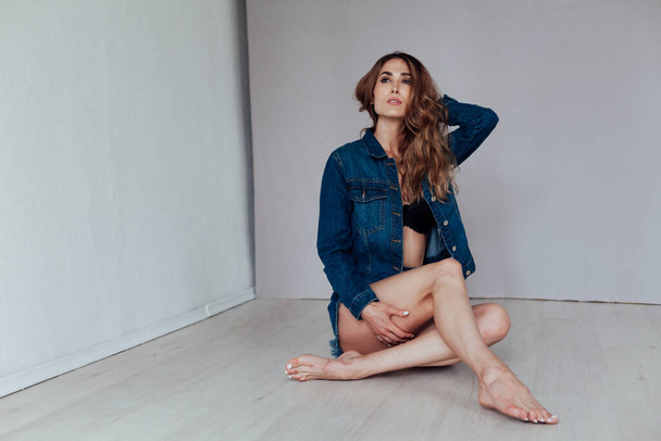 Portrait of a beautiful fashionable woman in black lingerie and denim shorts - 写真・画像
