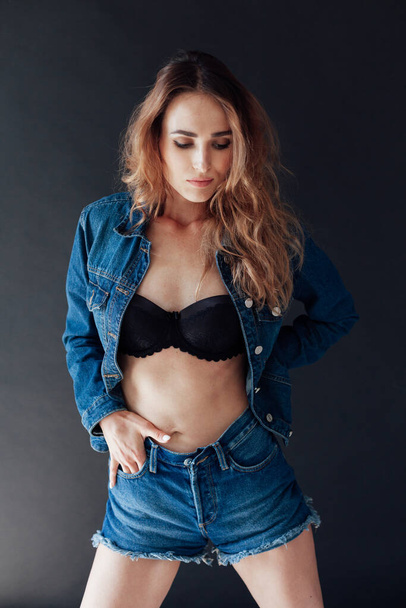 Portrait of a beautiful fashionable woman in black lingerie and denim shorts - Photo, image
