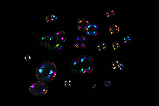 Zeepbellen geïsoleerd op een zwarte achtergrond. Kopieerruimte.  - Foto, afbeelding
