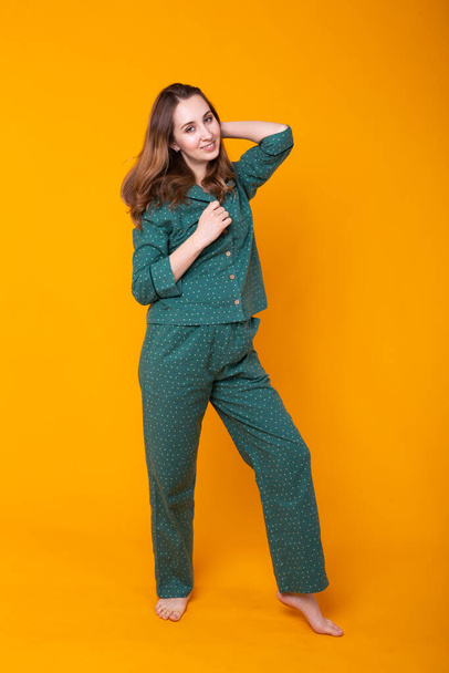 Young girl posing in pajamas on yellow background. Relax good mood, lifestyle and sleepwear concept. - Photo, Image
