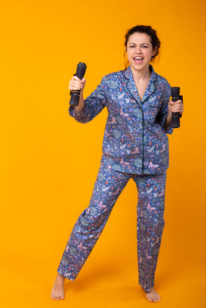 Young girl posing in pajamas on yellow background. Relax good mood, lifestyle and sleepwear concept. - Foto, Imagem