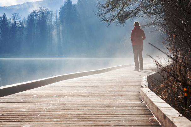秋の霧に包まれた日の出に湖で一人で - 写真・画像
