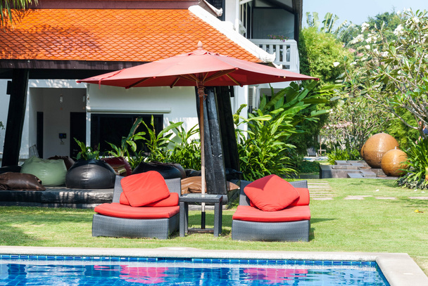 Red beach chairs with red umbrella aside swimming-pool - Foto, imagen