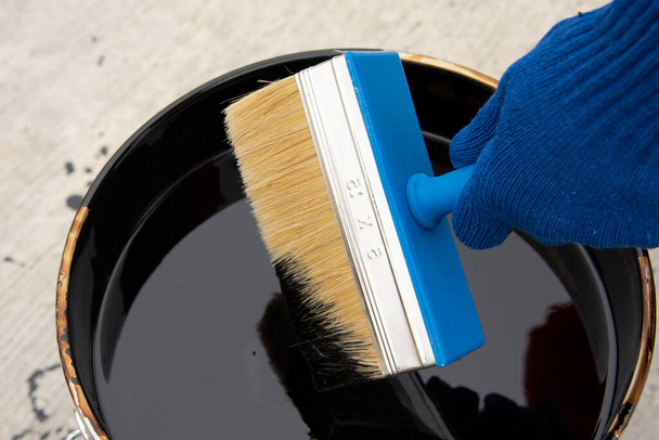 Roofers hand in blue mittens holding a brush - Photo, Image