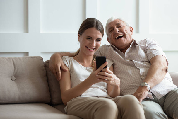 Excited mature dad and adult daughter using smartphone - Photo, image