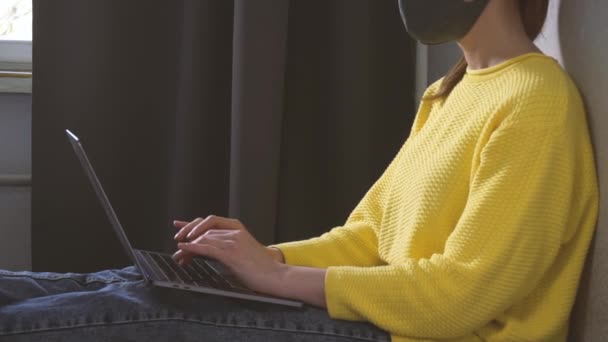 Vrouw in masker werken vanuit huis op laptop - Video