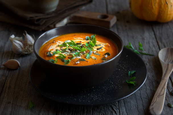 Гарбузовий суп з вершками, петрушкою та гарбузовим насінням на темряві
 - Фото, зображення