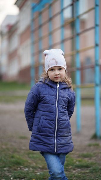 スウェーデンのはしごの近くの遊び場にポーズ赤い帽子のかわいい女の子の肖像画。子供が手を取り合って笑顔で - 写真・画像