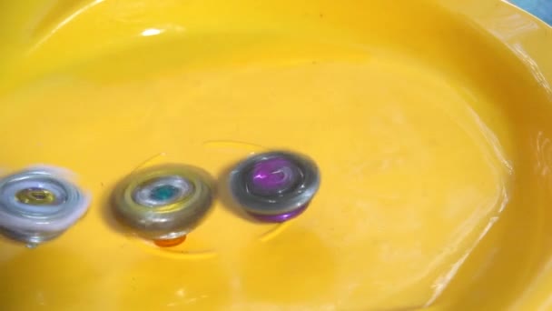 Collective image of the children's popular toy Beyblade. The battle of two Beyblade in the arena in a flat style.Slow motion. - Footage, Video
