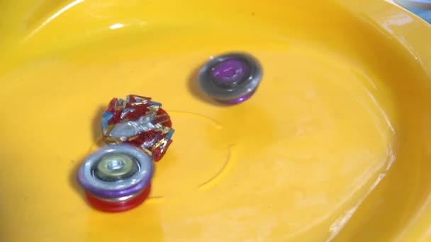Collective image of the children's popular toy Beyblade. The battle of two Beyblade in the arena in a flat style.Slow motion. - Footage, Video
