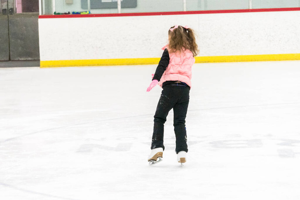 Meisje oefenen kunstschaatsen beweegt op de indoor ijsbaan. - Foto, afbeelding