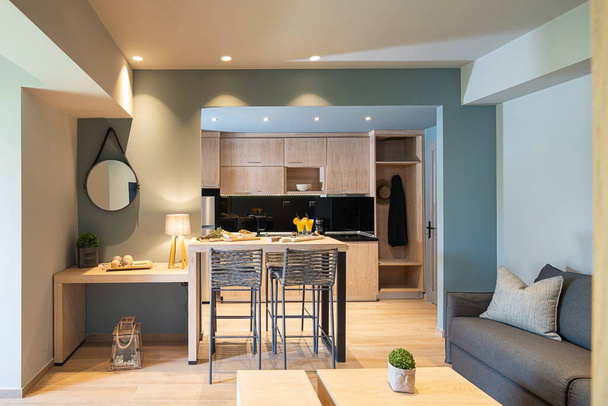 Современный серый и деревянный интерьер небольшой однокомнатной квартиры. Вид спереди на гостиную, кухню, гостиную, спальню в одноместном пространстве
 - Фото, изображение