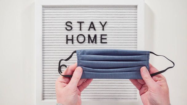 Flat lay. STAY HOME and COVID-19 sign on message board with a homemade face mask. - Foto, Imagem
