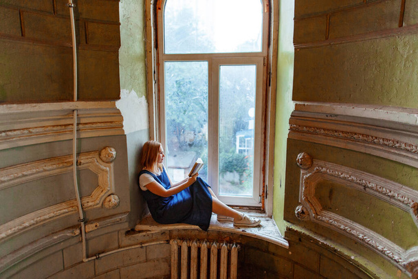 woman sits of window in old house and reads book - Foto, immagini