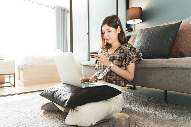 Young Asian woman using credit card for shopping online at her home - Foto, imagen