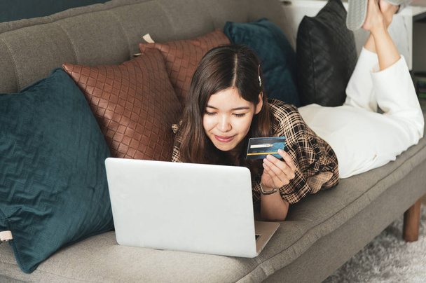 Giovane donna asiatica utilizzando la carta di credito per lo shopping online a casa sua
 - Foto, immagini